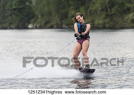 A teenage girl wakeboarding behind a boat on a lake; Lake of the Woods, Ontario, Canada View Large Photo Image Stock Photograph - A teenage girl wakeboarding behind a boat on a lake; Lake of the Woods, Ontario, Canada. Fotosearch