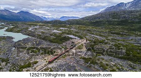 Stock Photograph - A train runs through the barren landscape on its way to Carcross; Yukon Territory, Canada. Fotosearch