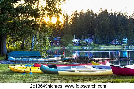A variety of coloured canoes and kayaks on the shore of a camp at sunrise, Lakeside Camp; Whidbey Island, Washington, United States of America View Large Photo Image Stock Photograph - A variety of coloured canoes and kayaks on the shore of a camp at sunrise, Lakeside Camp; Whidbey Island, Washington, United States of America. Fotosearch