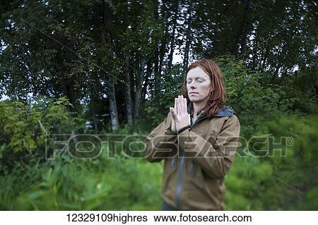 Stock Photograph - A woman do yoga in a forest; Homer, Alaska, United States of America. Fotosearch
