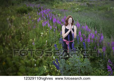 Stock Photograph - A woman do yoga in a meadow with wildflowers; Homer, Alaska, United States of America. Fotosearch