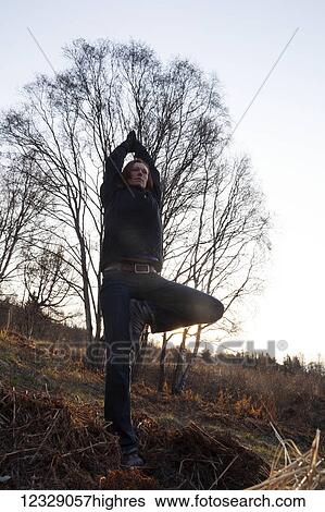 Stock Photograph - A woman does yoga on a hillside in autumn; Alaska, United States of America. Fotosearch