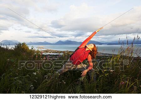 A woman doing yoga in a meadow with a view of Homer Spit, Kachemak Bay and the Kenai Mountains in the background; Homer, Alaska, United States of America View Large Photo Image Stock Photograph - A woman doing yoga in a meadow with a view of Homer Spit, Kachemak Bay and the Kenai Mountains in the background; Homer, Alaska, United States of America. Fotosearch