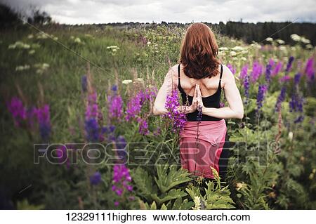 Stock Photograph - A woman doing yoga in a meadow with wildflowers; Homer, Alaska, United States of America. Fotosearch