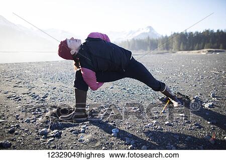 Stock Photograph - A woman doing yoga on the beach, Kenai Peninsula outer coast; Alaska, United States of America. Fotosearch
