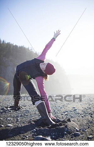 Stock Photograph - A woman doing yoga on the beach, Kenai Peninsula outer coast; Alaska, United States of America. Fotosearch