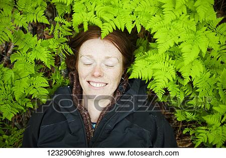 A woman lays her head on the forest floor among the bright green, lush ferns; Alaska, United States of America View Large Photo Image Stock Photograph - A woman lays her head on the forest floor among the bright green, lush ferns; Alaska, United States of America. Fotosearch