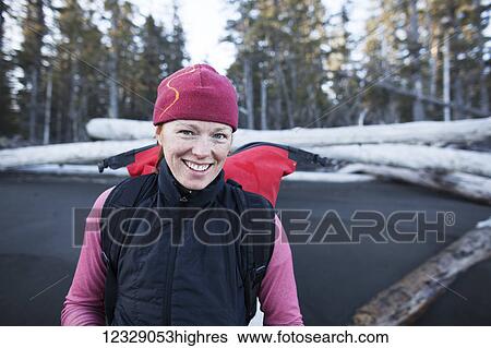 Stock Photograph - A woman standing on the beach carrying a backpack, Kenai Peninsula outer coast; Alaska, United States of America. Fotosearch