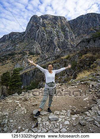 A woman stands posing in front of the stone walls and rugged mountains at Kotor Fortress; Kotor, Monte View Large Photo Image Stock Photograph - A woman stands posing in front of the stone walls and rugged mountains at Kotor Fortress; Kotor, Monte. Fotosearch