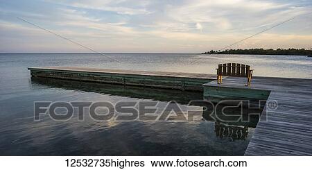 A wooden bench on a dock facing the coastline and open ocean at sunrise; Belize View Large Photo Image Stock Photograph - A wooden bench on a dock facing the coastline and open ocean at sunrise; Belize. Fotosearch