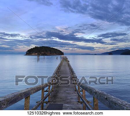 Stock Photograph - A wooden pier leading out into Bennet Bay in the Gulf Islands at sunset; Mayne Island, British Columbia, Canada. Fotosearch