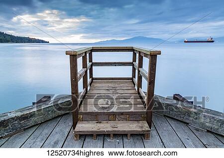 A wooden viewing platform at the end of a dock looks out to a ship on the tranquil ocean; Vancouver, British Columbia, Canada View Large Photo Image Stock Photograph - A wooden viewing platform at the end of a dock looks out to a ship on the tranquil ocean; Vancouver, British Columbia, Canada. Fotosearch