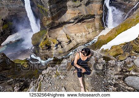 A young asian female hiker poses for a portrait on the edge of a stunning double waterfall valley landscape known as Haifoss; Iceland View Large Photo Image Stock Photograph - A young asian female hiker poses for a portrait on the edge of a stunning double waterfall valley landscape known as Haifoss; Iceland. Fotosearch