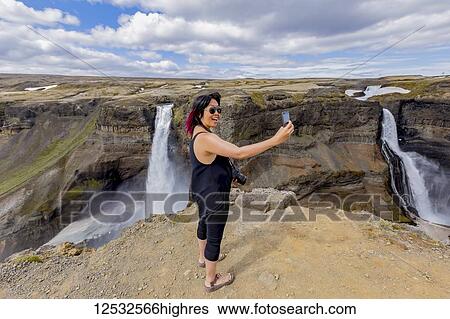 A young asian female hiker poses for a self-portrait on the edge of the Haifoss waterfall valley, a popular hiking destination in Iceland; Iceland View Large Photo Image Stock Photograph - A young asian female hiker poses for a self-portrait on the edge of the Haifoss waterfall valley, a popular hiking destination in Iceland; Iceland. Fotosearch