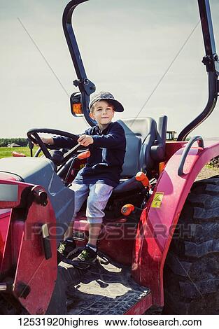 A young boy petending to ride a red tractor on a farm with his hat crooked on his head; Edmonton, Alberta, Canada View Large Photo Image Stock Photograph - A young boy petending to ride a red tractor on a farm with his hat crooked on his head; Edmonton, Alberta, Canada. Fotosearch