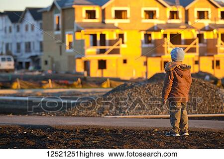 A young boy stands looking at new home construction in his neighbourhood; Langley, British Columbia, Canada View Large Photo Image Stock Photograph - A young boy stands looking at new home construction in his neighbourhood; Langley, British Columbia, Canada. Fotosearch