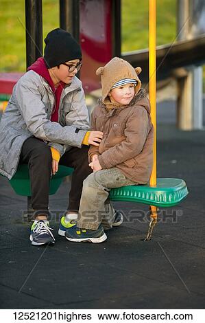 A young boy with his older brother sitting and talking at a playground; Langley, British Columbia, Canada View Large Photo Image Stock Photograph - A young boy with his older brother sitting and talking at a playground; Langley, British Columbia, Canada. Fotosearch