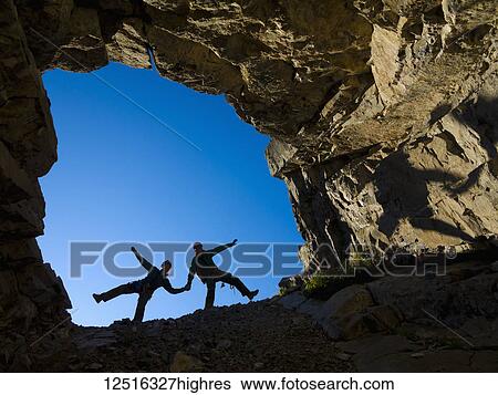 A young couple climbing in the mouth of a cave, holding hands and being playful; Fernie, British Columbia, Canada View Large Photo Image Stock Photograph - A young couple climbing in the mouth of a cave, holding hands and being playful; Fernie, British Columbia, Canada. Fotosearch