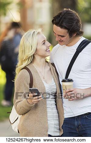 A young couple looking into each other's eyes and checking social media on a smart phone while walking through a university campus; Edmonton, Alberta, Canada View Large Photo Image Stock Photograph - A young couple looking into each other's eyes and checking social media on a smart phone while walking through a university campus; Edmonton, Alberta, Canada. Fotosearch