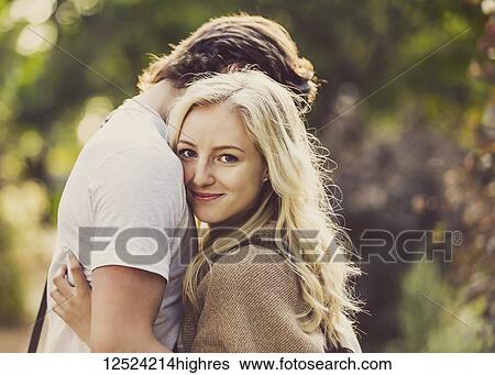 Stock Photograph - A young couple shares a romantic moment together in an embrace while outside on the university campus; Edmonton, Alberta, Canada. Fotosearch