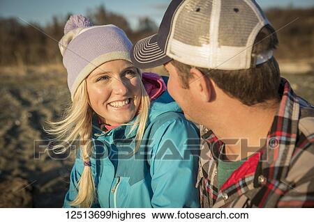 A young couple sits talking on a beach at sunset; Anchorage, Alaska, United States of America View Large Photo Image Stock Photograph - A young couple sits talking on a beach at sunset; Anchorage, Alaska, United States of America. Fotosearch