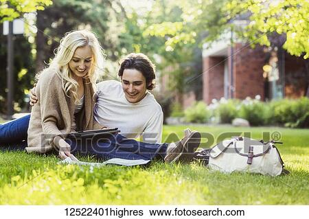 A young couple studying outdoors on the grass on the university campus and looking through a textbook while using a tablet; Edmonton, Alberta, Canada View Large Photo Image Stock Photograph - A young couple studying outdoors on the grass on the university campus and looking through a textbook while using a tablet; Edmonton, Alberta, Canada. Fotosearch