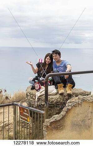 A young couple taking a selfie photo with a selfie stick and smart photo on Diamond Head; Oahu, Hawaii, United States of America View Large Photo Image Stock Photo - A young couple taking a selfie photo with a selfie stick and smart photo on Diamond Head; Oahu, Hawaii, United States of America. Fotosearch