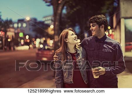 A young couple walks down a sidewalk in a popular trendy area at dusk; Edmonton, Alberta, Canada View Large Photo Image Stock Photograph - A young couple walks down a sidewalk in a popular trendy area at dusk; Edmonton, Alberta, Canada. Fotosearch