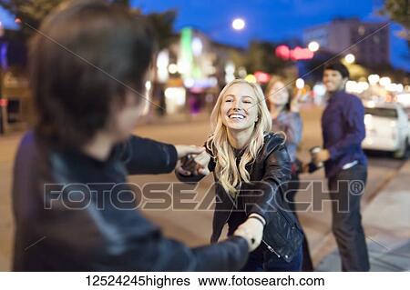 A young couple wearing black leather jackets being playful on a city sidewalk at night with friends watching in the background; Edmonton, Alberta, Canada View Large Photo Image Stock Photograph - A young couple wearing black leather jackets being playful on a city sidewalk at night with friends watching in the background; Edmonton, Alberta, Canada. Fotosearch