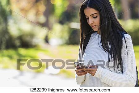 A young female student of Lebanese ethnicity checking her smart phone while walking in a university campus; Edmonton, Alberta, Canada View Large Photo Image Stock Photograph - A young female student of Lebanese ethnicity checking her smart phone while walking in a university campus; Edmonton, Alberta, Canada. Fotosearch