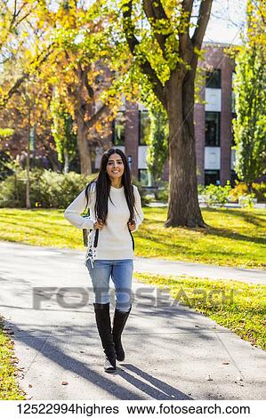 Stock Photograph - A young female university student of Lebanese ethnicity walking on a path on campus with a backpack; Edmonton, Alberta, Canada. Fotosearch