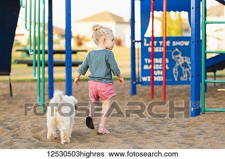 Stock Photograph - A young girl and her pet dog playing in a playground on a warm fall day; Spruce Grove, Alberta, Canada. Fotosearch