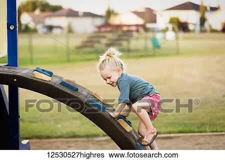 A young girl with blond hair playing in a playground and climbing up a rock ladder on a warm fall day; Spruce Grove, Alberta, Canada View Large Photo Image Stock Photograph - A young girl with blond hair playing in a playground and climbing up a rock ladder on a warm fall day; Spruce Grove, Alberta, Canada. Fotosearch