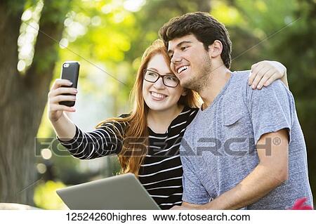 A young man and young woman taking a self-portrait on a smart phone; Edmonton, Alberta, Canada View Large Photo Image Stock Photograph - A young man and young woman taking a self-portrait on a smart phone; Edmonton, Alberta, Canada. Fotosearch