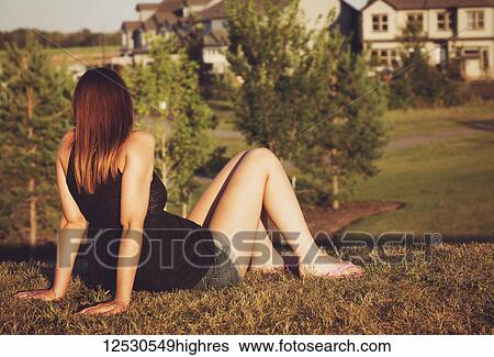 Stock Photograph - A young pregnant woman relaxing in a park in the warmth of the setting sun on beautiful fall evening; Spruce Grove, Alberta, Canada. Fotosearch