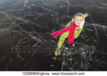 Stock Photograph - A young woman poses while ice skating on a frozen lake; Alaska, United States of America. Fotosearch