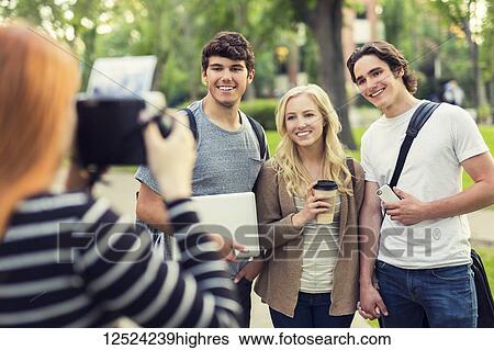 A young woman takes a picture of three friends on a university campus; Edmonton, Alberta, Canada View Large Photo Image Stock Photograph - A young woman takes a picture of three friends on a university campus; Edmonton, Alberta, Canada. Fotosearch