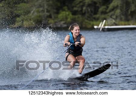 A young woman wakeboarding behind a boat on a lake; Lake of the Woods, Ontario, Canada View Large Photo Image Stock Photograph - A young woman wakeboarding behind a boat on a lake; Lake of the Woods, Ontario, Canada. Fotosearch