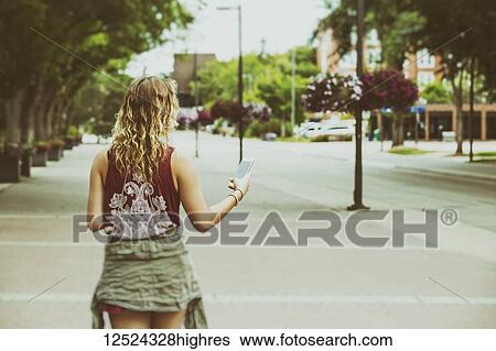 A young woman walks down a path on a university campus reading from her smart phone; Edmonton, Alberta, Canada View Large Photo Image Stock Photograph - A young woman walks down a path on a university campus reading from her smart phone; Edmonton, Alberta, Canada. Fotosearch