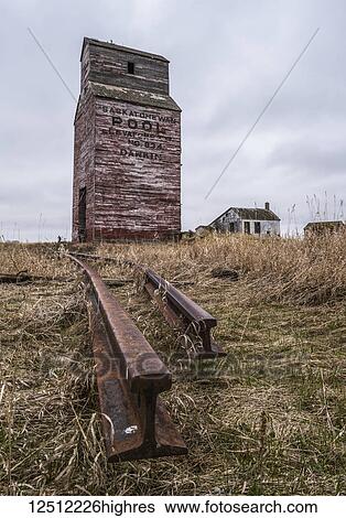 Stock Photograph - Abandoned grain elevator with rusted railroad tracks in rural Saskatchewan; Saskatchewan, Canada. Fotosearch