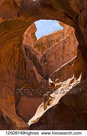 Adventure athlete in the womb of a giant slot canyon bowl; Hanksville, Utah, United States of America View Large Photo Image Stock Photograph - Adventure athlete in the womb of a giant slot canyon bowl; Hanksville, Utah, United States of America. Fotosearch