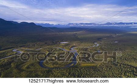 Stock Photograph - Aerial image of a stream with the mountains of Kluane National Park in the distance, near Haines Junction; Yukon Territory, Canada. Fotosearch