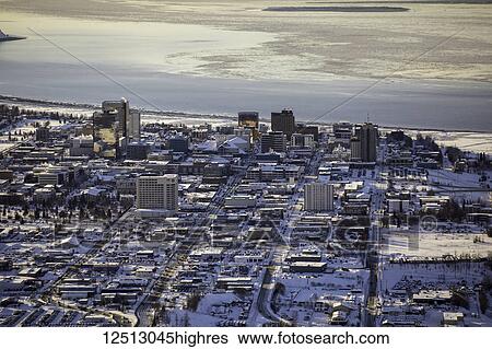 Stock Photograph - Aerial view of 3rd, 4th, 5th and 6th avenues running West towards the ocean through downtown Anchorage, sea ice on Cook Inlet in the background, the Marriot, Hilton and Captain Cook Hotels visible in the foreground, South-central Alaska; Anchorage,.... Fotosearch