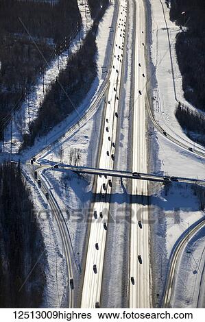 Aerial view of snow covering a highway overpass on the Glenn Highway in winter, the late evening sun casting long black shadows across the cars driving on the highway, South-central Alaska; Anchorage, Alaska, United States of America View Large Photo Image Stock Photograph - Aerial view of snow covering a highway overpass on the Glenn Highway in winter, the late evening sun casting long black shadows across the cars driving on the highway, South-central Alaska; Anchorage, Alaska, United States of America. Fotosearch