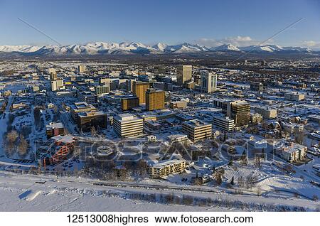 Stock Photograph - Aerial view of snow covering downtown Anchorage and the the Chugach Mountains in the distance, the Capitan Cook Hotel and Conoco Philips buildings in the foreground, South-central Alaska in winter; Anchorage, Alaska, United States of America. Fotosearch