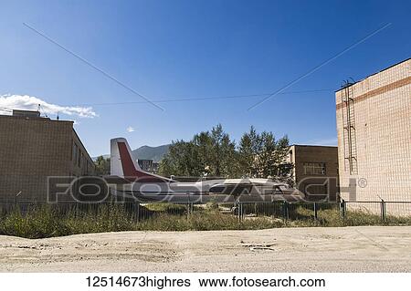 Stock Photograph - An old, abandoned plane parked between buildings and behind a fence; Ulaanbaatar, Ulaanbattar, Mongolia. Fotosearch