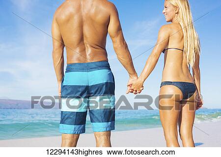 Stock Photograph - Attractive Couple On Sunny Tropical Beach Vacation. Fotosearch