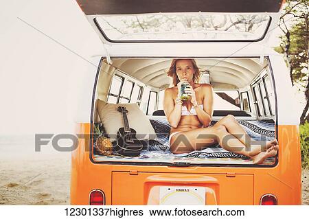 Stock Photograph - Beach Lifestyle, Beautiful Surfer Girl On The Beach At Sunset With Classic Vintage Surf Van. Fotosearch