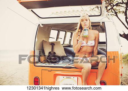 Stock Photograph - Beach Lifestyle, Beautiful Surfer Girl On The Beach At Sunset With Classic Vintage Surf Van. Fotosearch
