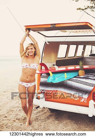 Stock Photograph - Beach Lifestyle, Beautiful Surfer Girl On The Beach At Sunset With Classic Vintage Surf Van. Fotosearch
